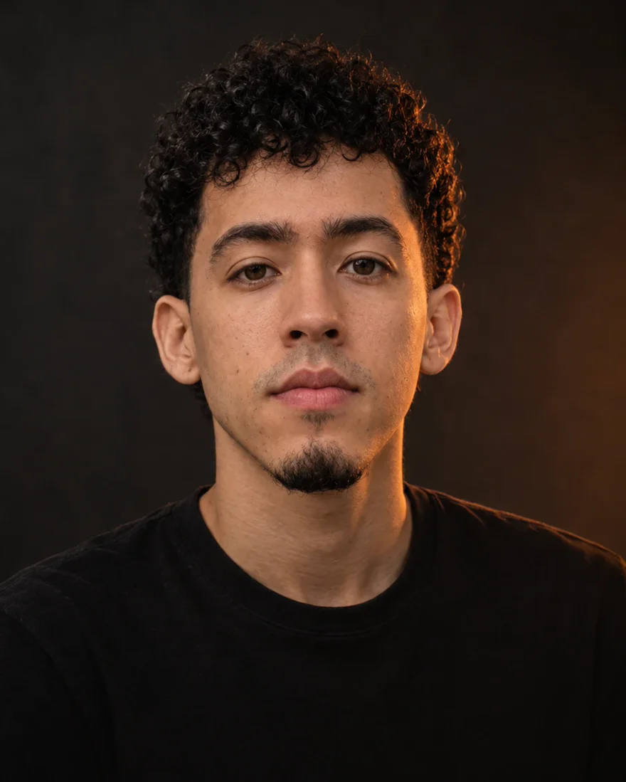 Retrato de Juan Pablo Peláez, fundador de Pelaez Studio, con luz ámbar de estudio sobre fondo oscuro